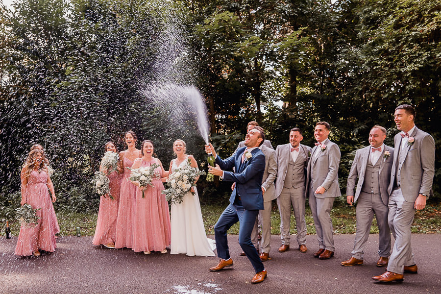 bridal party opening a bottle of fizz