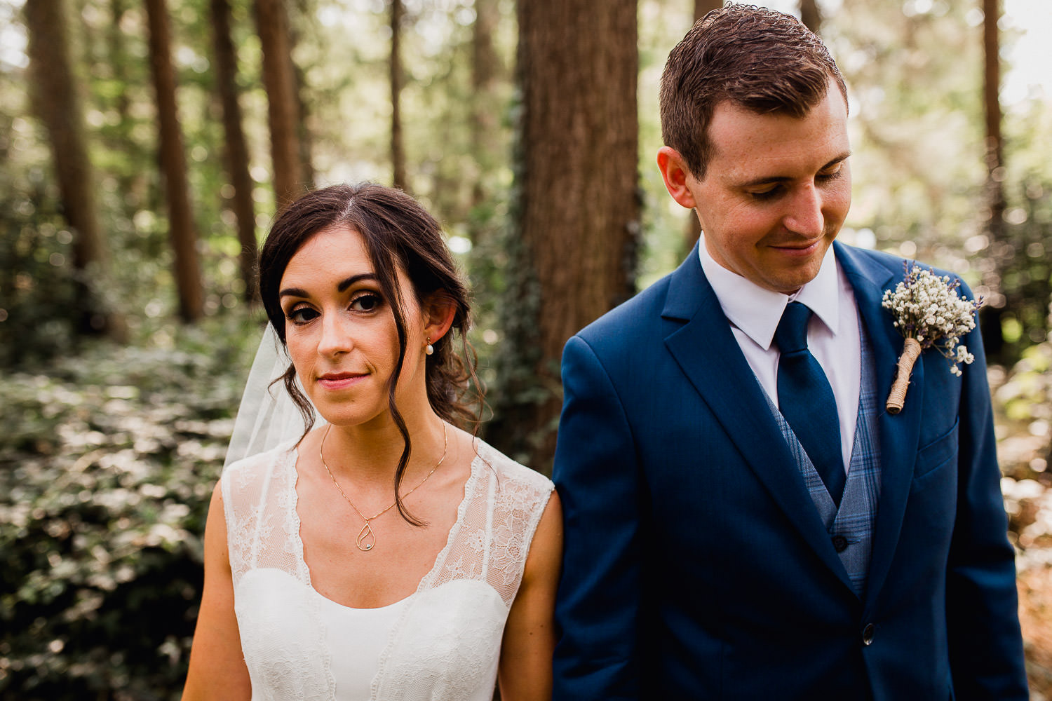 bride and groom standing in a forest