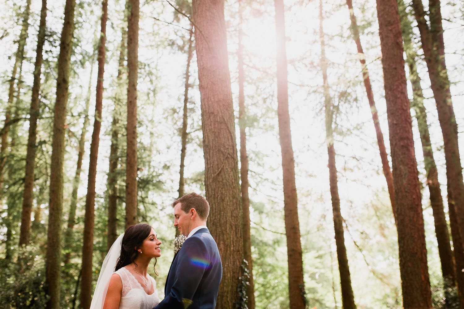bride and groom standing in a forest