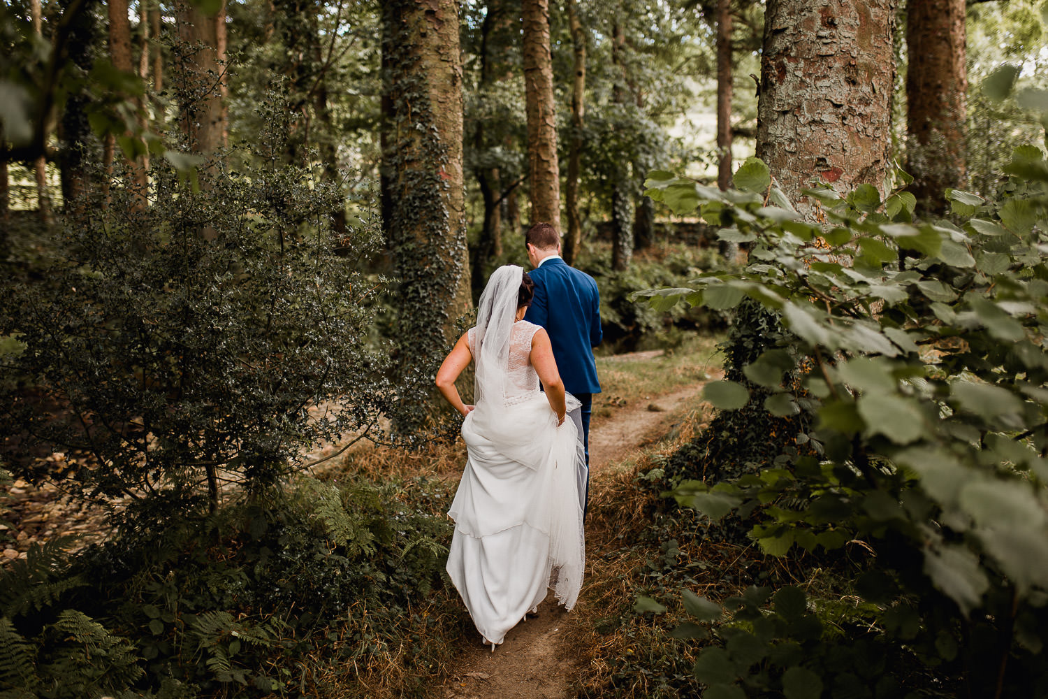 bride and groom walking through a forest