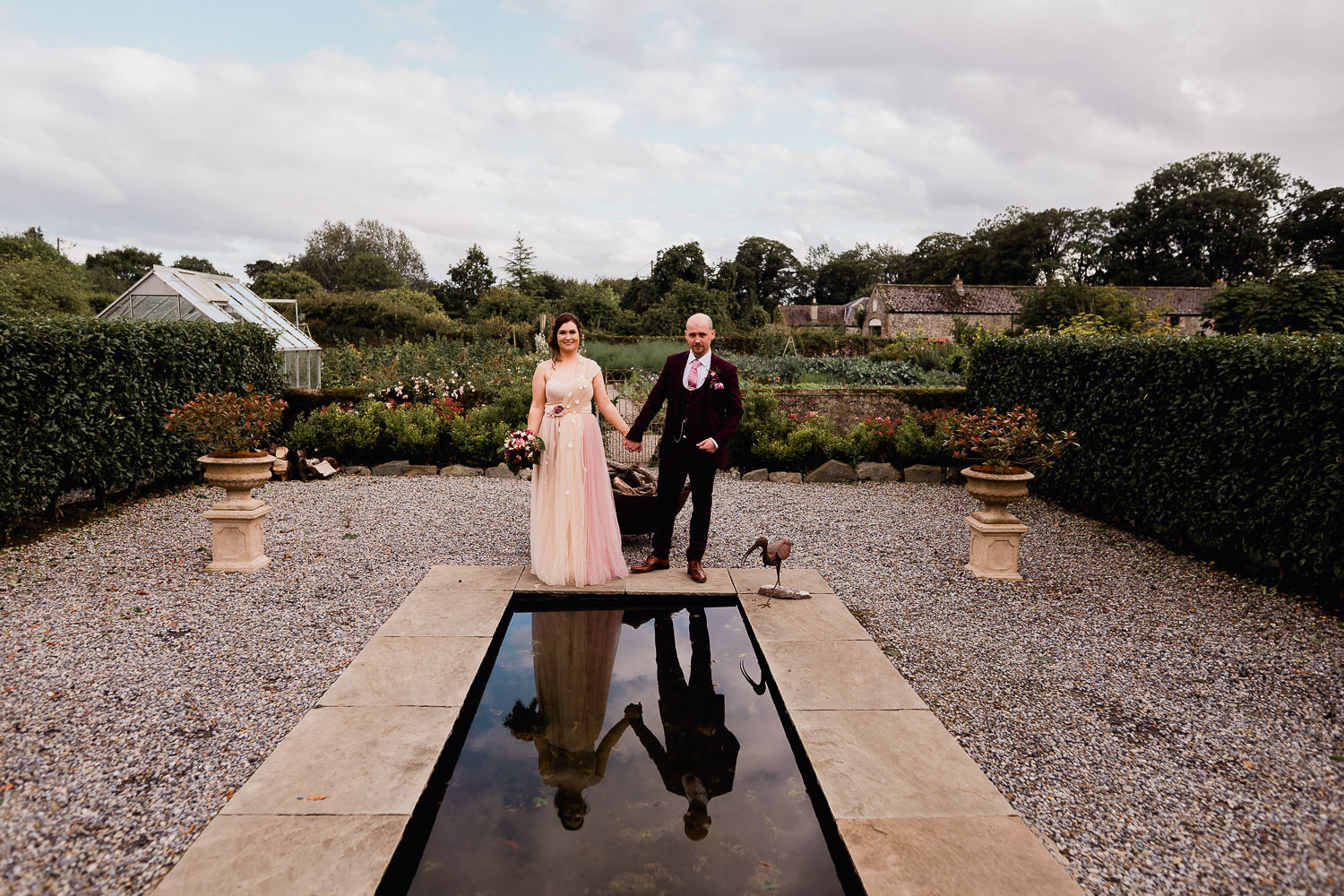 bride and groom standing in front of a pond