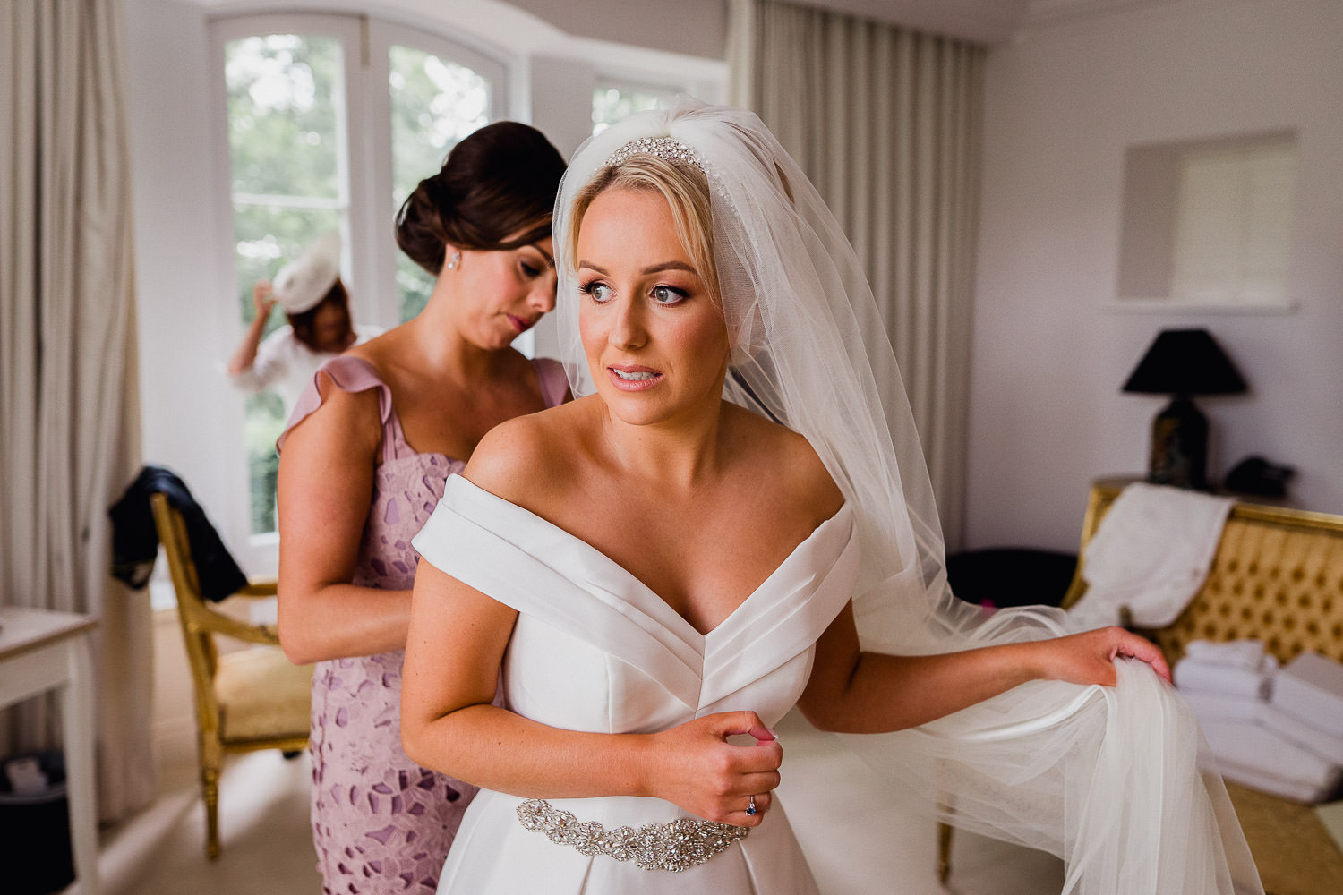 bridesmaid helping the bride with her dress