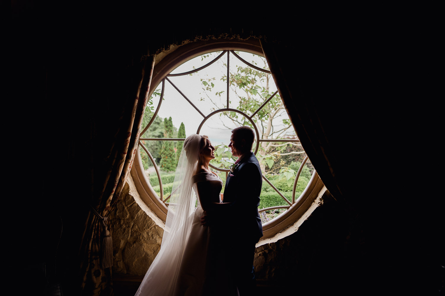 bride and groom standing in window light