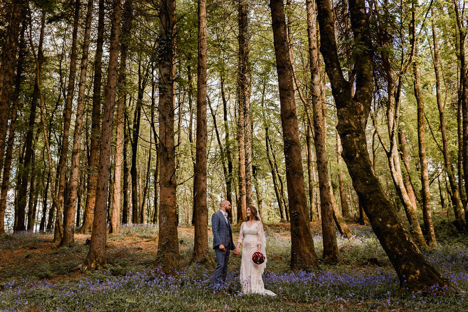 bride and groom standing in a bluebell forest