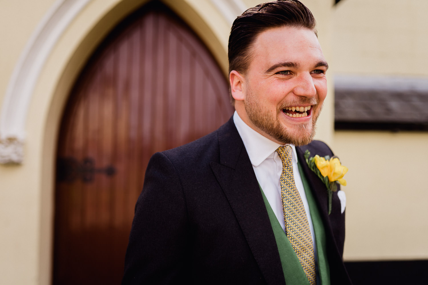 groom laughing outside a church