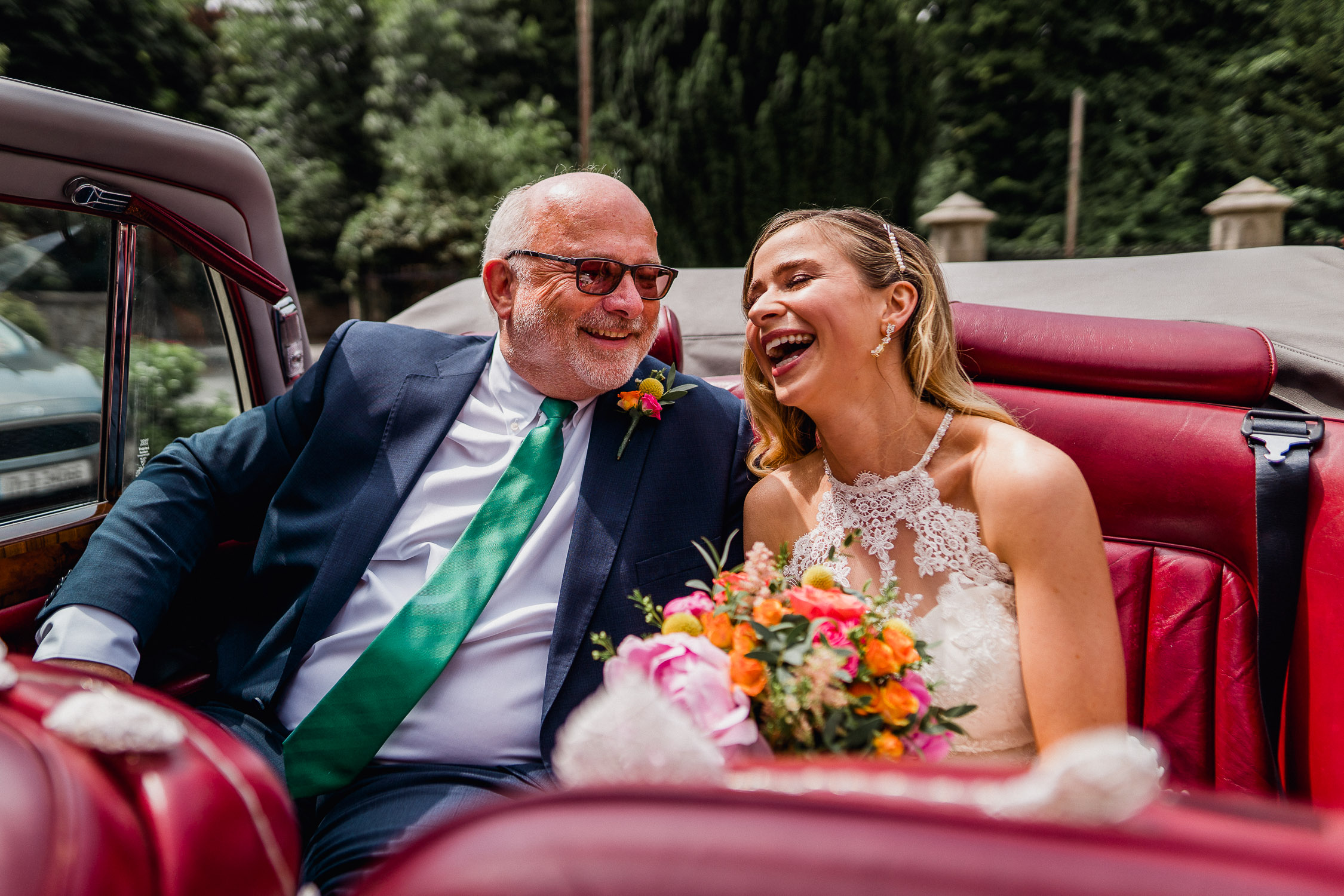 bride and her father sitting in a car laughing