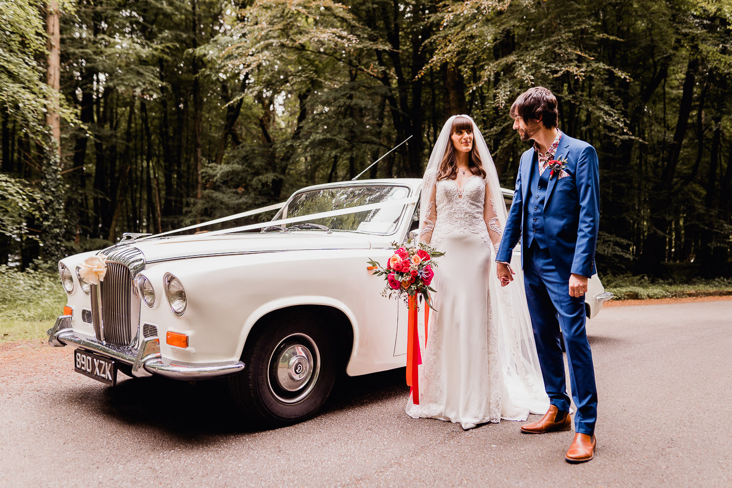 bride and groom holding hands in front of a white car